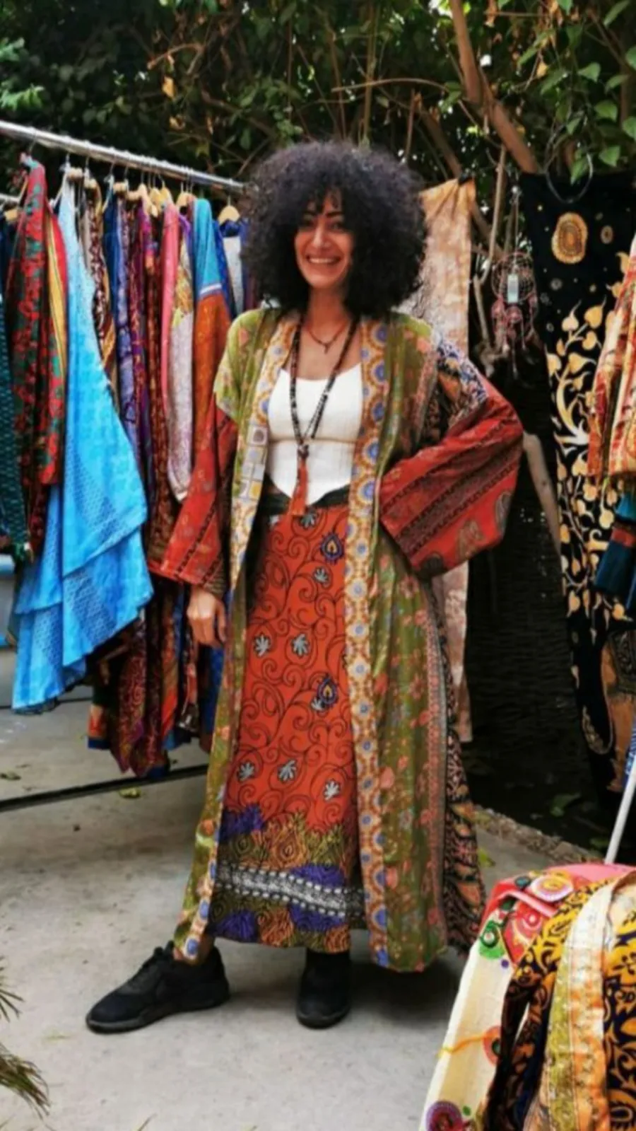 Reyam El Molla in a patchwork kimono in front of a rack of saris
